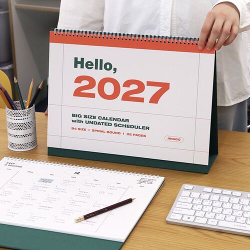 A desktop arrangement pairs the calendar with an open notebook, showing how its large pages suit organized planning.