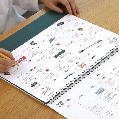 A close-up highlights the open monthly layout, outlined writing areas, and clearly marked date columns.