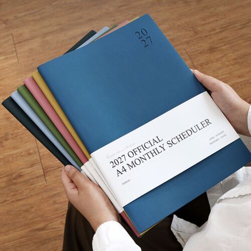 Several color options fan out behind the Navy Blue cover, highlighting the scheduler’s coordinated finish and substantial page size.