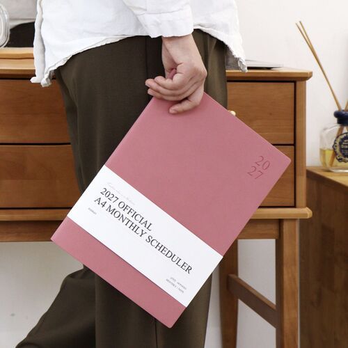 The Dusty Rose cover is carried by hand, giving a clear sense of the scheduler’s large but manageable format.