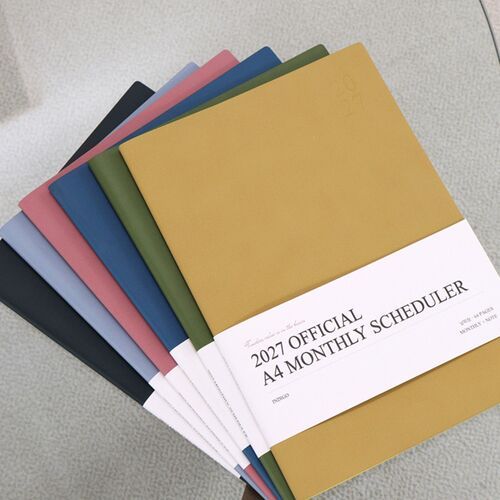 A laptop, pen, and open monthly scheduler create a practical desk scene for coordinating digital and handwritten plans.