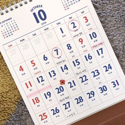 The spiral-bound calendar rests open on a tabletop beside stationery, ready for everyday scheduling.