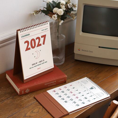 The open calendar is shown on a wooden desk with the monthly grid spread flat for writing and reviewing plans.