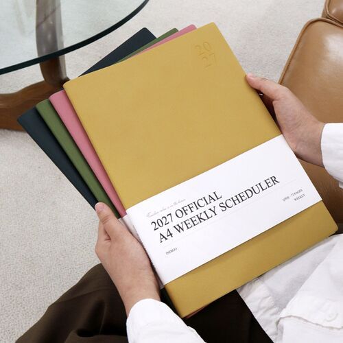 A Mustard scheduler is shown closed on a desk, with its embossed 2027 marking and white title band visible.