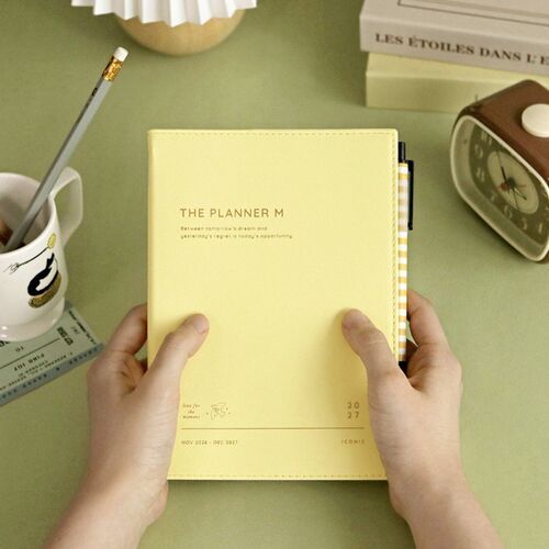 Butter appears in hand beside a striped pen, giving a clear view of the cover texture and compact vertical format.