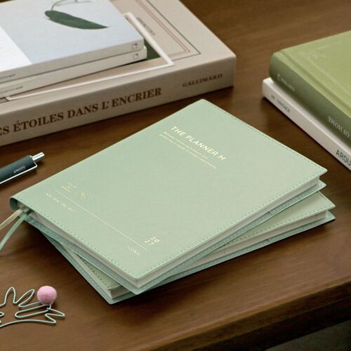 Cream Mint rests on a tabletop with layered pages and ribbon bookmarks visible along the lower edge.