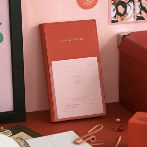 The Vermilion planner stands upright with its textured cover, stitched edges, and front pocket clearly visible.