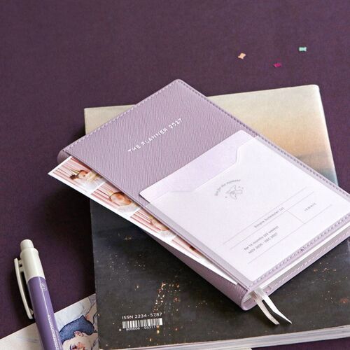 A Lavender planner rests open on a dark surface with both ribbon bookmarks extending from the bottom edge.