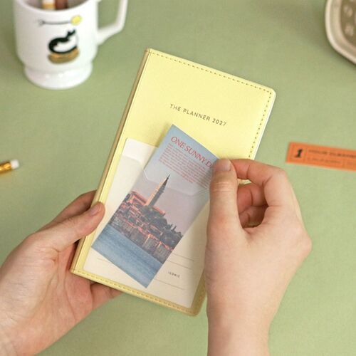 The open planner shows a dated monthly grid, a ribbon bookmark, and a pen held neatly along the side.