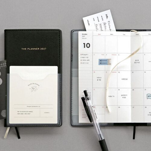 The planners stand together in a clear holder, revealing their textured covers, rounded corners, and stitched edges.