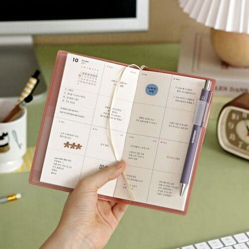 Lavender and Black planners are staged with books and a clip, showing how neatly they fit into a workspace.