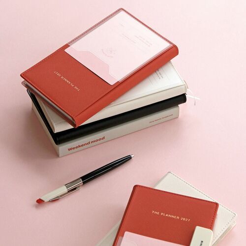 A shelf display features Lavender and Butter planners standing upright among books and simple desk decor.