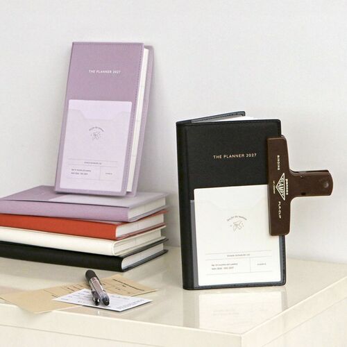 A bright shelf scene shows the planner collection arranged with notebooks, stationery, and everyday desk accessories.