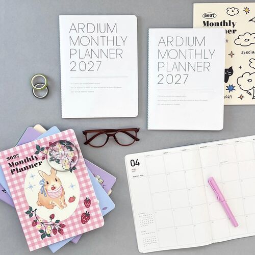 A desk scene pairs the planner with stationery and glasses, showing how comfortably the large format fits a planning workspace.