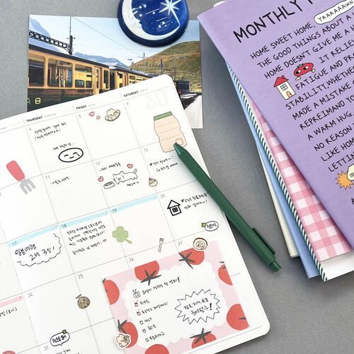 The open planner displays a grid-style note page alongside the Green cover's illustrated woodland landscape.