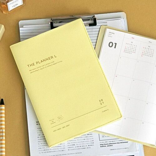 Lemon Yellow sits over an open monthly spread, showing the planner’s clean cover texture and spacious format.