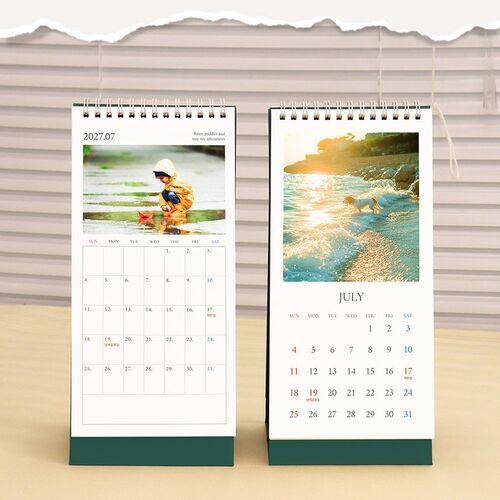 July pages show photographic imagery and date grids while the calendar stands neatly against a bright window backdrop.