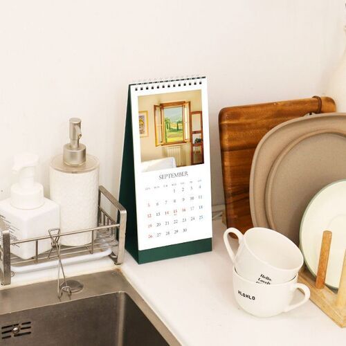 The calendar rests beside a sink and kitchen accessories, illustrating its usefulness for tracking household plans at a glance.