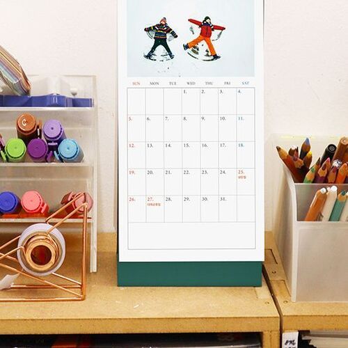 A standing monthly page fits between desk organizers, pens, and markers, with ample room for notes beneath the image.