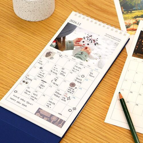 A January page stands near kitchen items, pairing its ocean-sunset photograph with a clearly visible monthly grid.