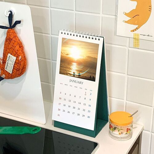 The calendar is shown beside travel and interior imagery, emphasizing its photo-led page design and slim vertical presentation.
