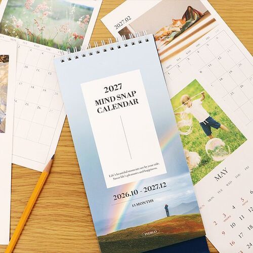 Pages and covers spread across a wooden table, giving a closer look at the Rainbow option and monthly calendar sheets.