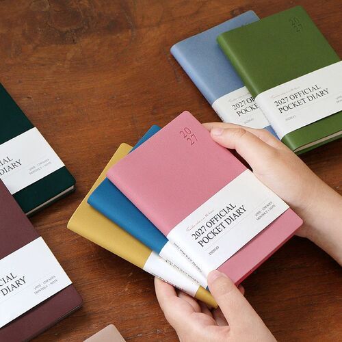 Green Mousse and Water Blue planners rest on a wooden surface with their dated covers and wrapped labels clearly visible.
