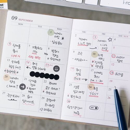 A September spread is shown beside a laptop with colorful notes and marked dates filling the monthly grid.