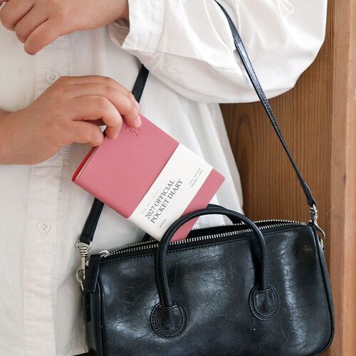 Red Bean stands on a stack of planners, highlighting the cohesive spine presentation and softly rounded cover edges.