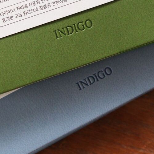 Teal Blue is held in one hand above a stack, emphasizing the pocket planner’s compact proportions and bold cover color.