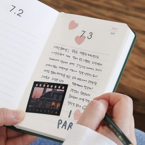 Tomato Red lies open on a desk with illustrated daily pages and a pen ready for writing or journaling.