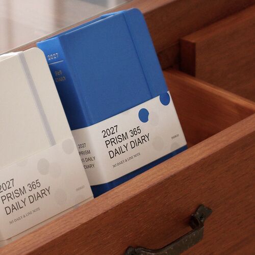 The final arrangement places several Prism planners upright and open, giving a clear view of the colorful covers and daily format.