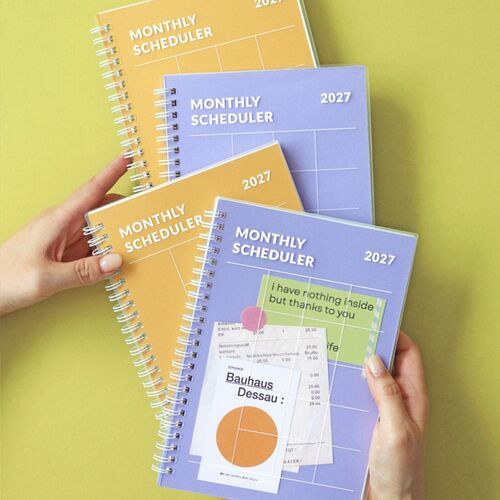 The Orange planner is centered on a yellow surface, displaying its roomy cover grid and clear outer cover.