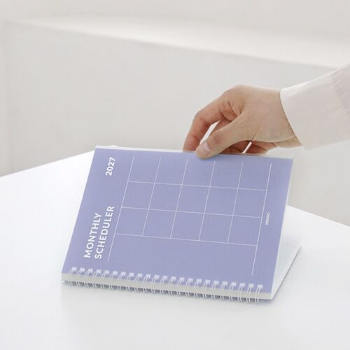 The Orange planner rests inside a backpack compartment while being removed, highlighting its portable spiral-bound design.
