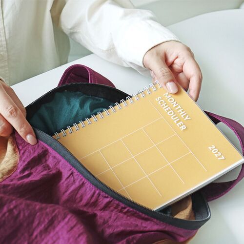 An Orange planner is placed inside an open backpack, showing its convenient format for carrying between locations.