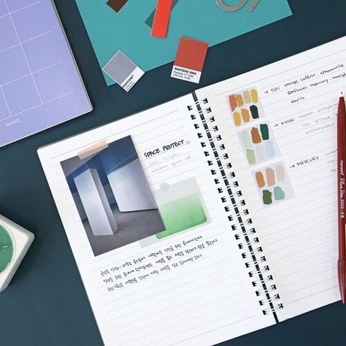 A monthly spread is paired with colorful stationery and a pen, illustrating a desk-based planning session.