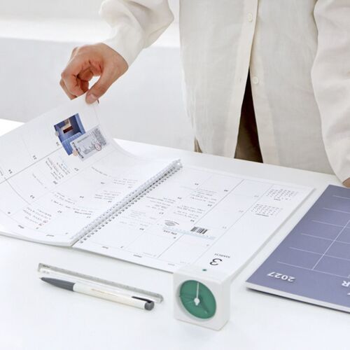 An open planner is shown in use on a desk, with a dated monthly spread ready for appointments and notes.