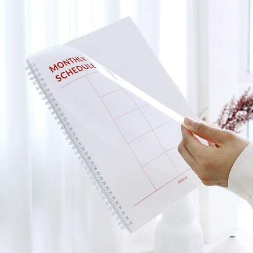 A close view shows the White cover’s red Monthly Scheduler title and the roomy rectangular planning sections.