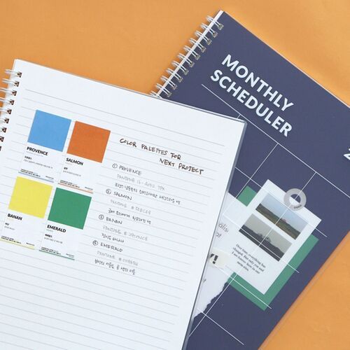 A tabletop comparison shows both cover colors, their silver spirals, and the red printed planner titles.