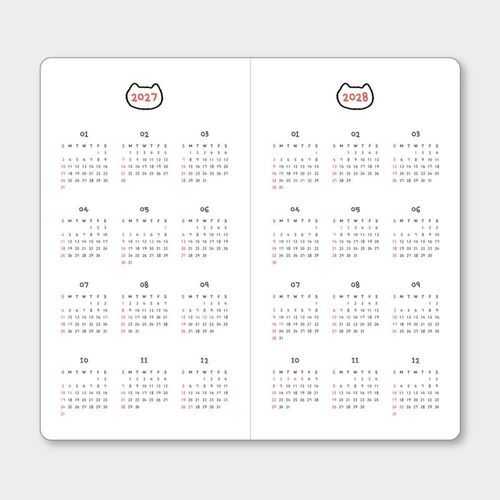 A hand writes in the monthly grid beside the Birthday Cat cover, showing the planner’s practical layout during everyday use.