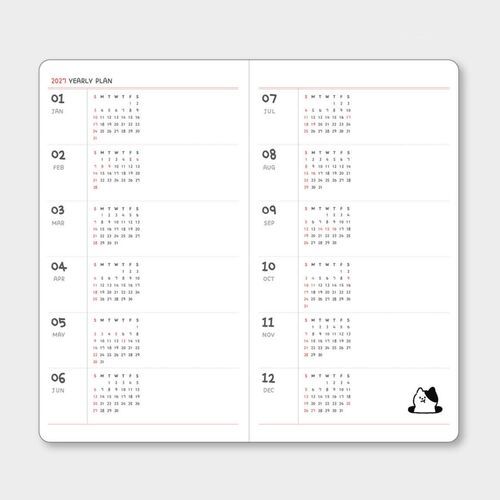 The planner is styled with stationery and desk accessories, showing how the compact format fits naturally into a planning setup.