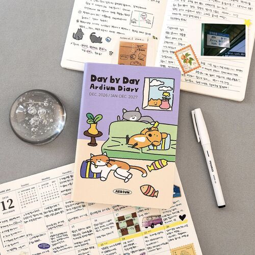 A daily page is styled with stickers, handwritten notes, a photograph, and decorative pieces to demonstrate journaling and memory keeping.