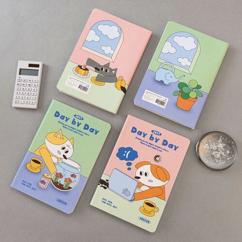 A desk-style arrangement places several covers around an open monthly spread, highlighting the planner’s colorful design and practical calendar format.