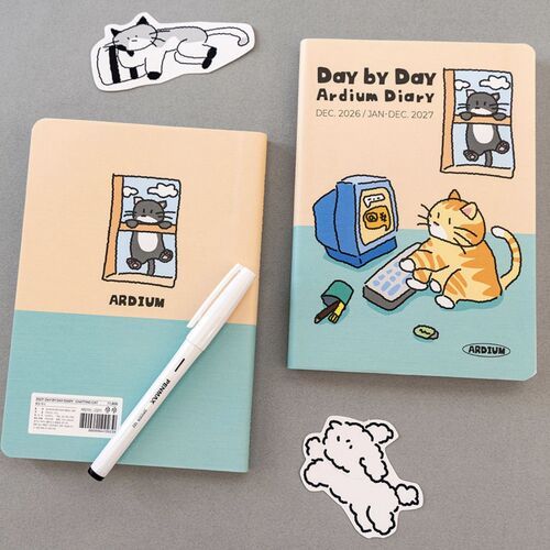 The Happy Puppies planner rests beside a black pen, while its illustrated cover and December 2026 start date remain clearly visible.