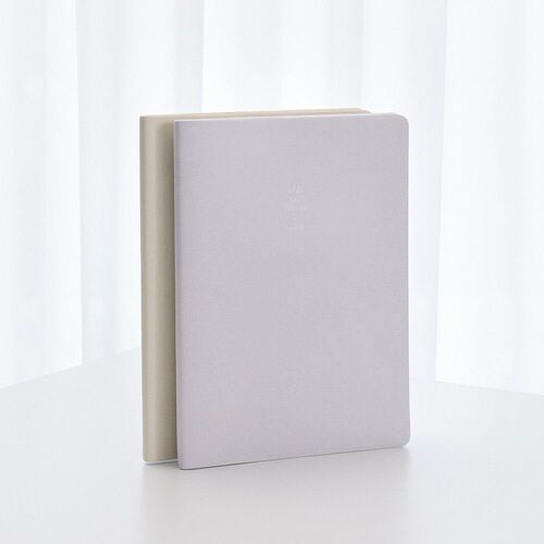 Two closed planners stand together, highlighting the rounded corners and softly textured covers in pale neutral tones.