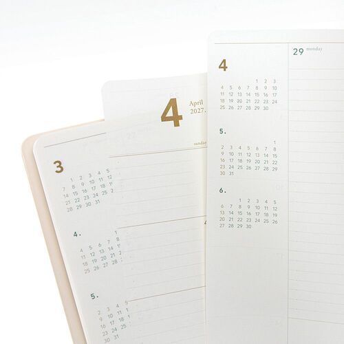 Several planners are stacked by size in a bright room, showing the slim construction and softly rounded covers.