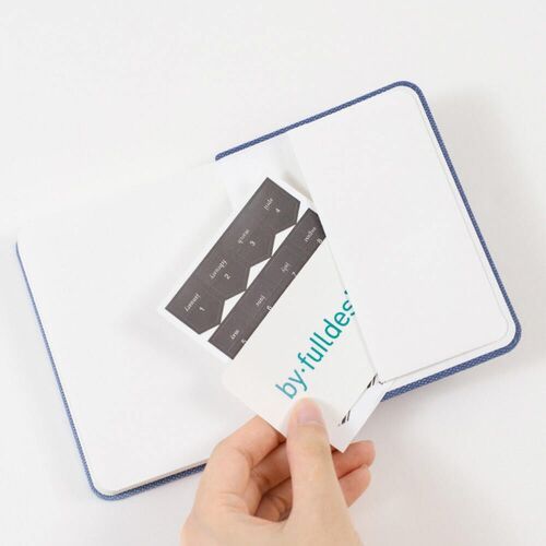 A sticker sheet is placed over an open planner, showing the included index stickers and coordinating cover colors.