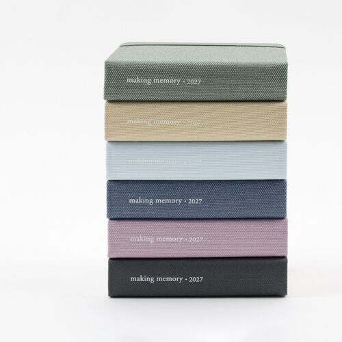 Four planners are stacked vertically, showing the cover texture, rounded edges, and printed 2027 spine details.