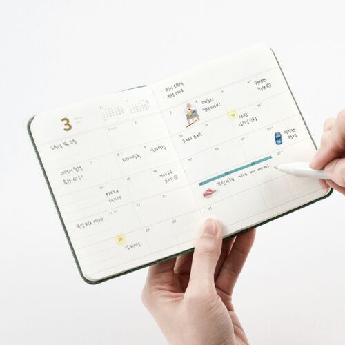 A hand writes across a March 2027 monthly layout, demonstrating room for events, reminders, and personal highlights.