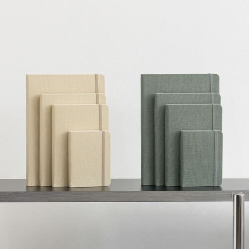 A gray-covered planner lies open with a pencil across its lined pages and a simple habit-tracking layout.